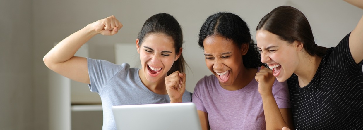 Drie meiden checken de laptop tijdens een verhuizing en zijn blij