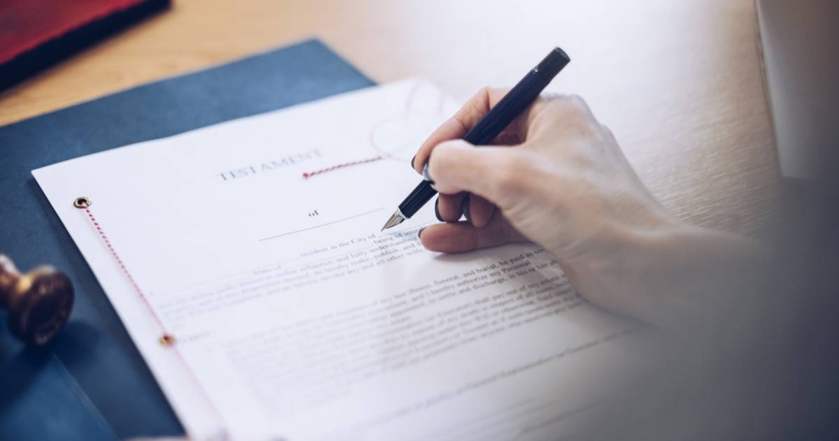 Een vrouw achter een bureau met een testament voor haar en een pen in haar hand